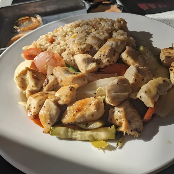 Hibachi chicken with fried rice and vegetables, including carrots, onions, and zucchini.